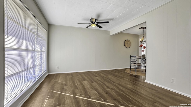 unfurnished room with ceiling fan with notable chandelier and dark wood-type flooring