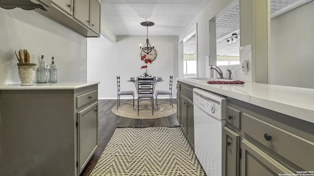 kitchen with white dishwasher, sink, gray cabinets, dark hardwood / wood-style floors, and hanging light fixtures