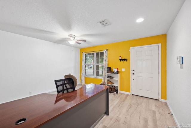 office featuring ceiling fan, light wood-type flooring, and a textured ceiling