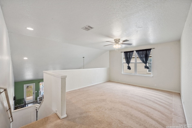 unfurnished room with light carpet, a textured ceiling, ceiling fan, and lofted ceiling