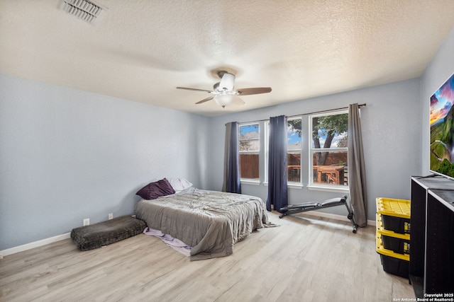 bedroom featuring a textured ceiling, light wood-type flooring, and ceiling fan