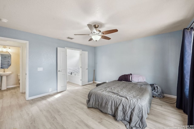 bedroom featuring ensuite bathroom, sink, ceiling fan, and light wood-type flooring