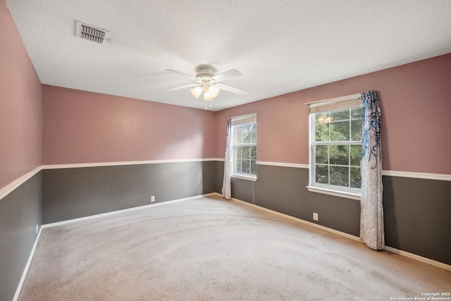 carpeted spare room featuring ceiling fan and a textured ceiling