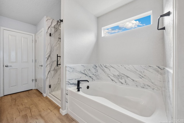 bathroom featuring hardwood / wood-style floors, separate shower and tub, and a textured ceiling