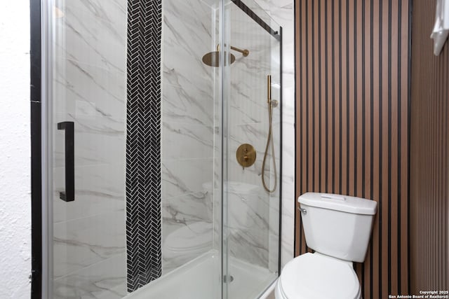 bathroom with a shower with shower door and toilet