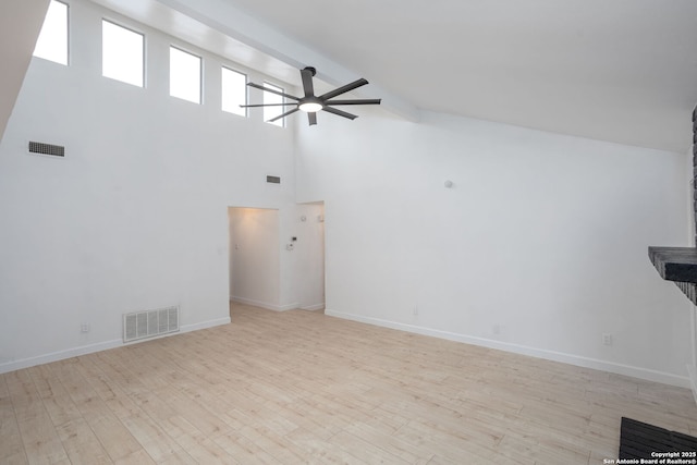 unfurnished living room with beamed ceiling, a towering ceiling, light hardwood / wood-style floors, and ceiling fan