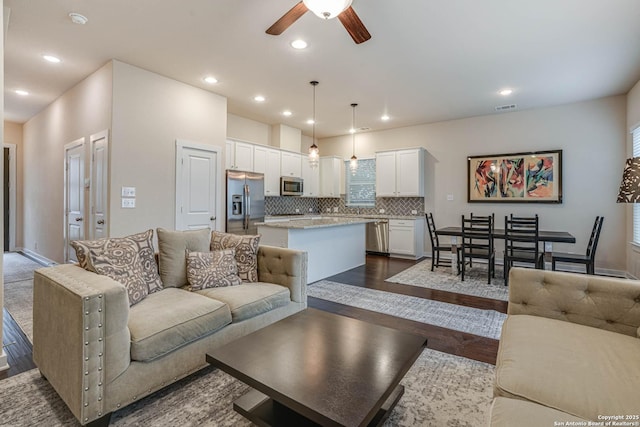 living room featuring dark hardwood / wood-style flooring and ceiling fan