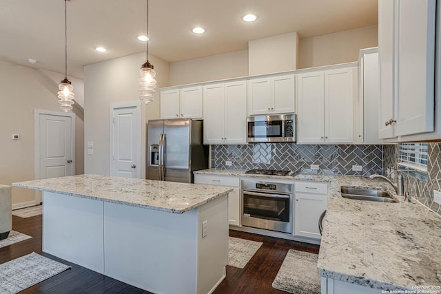 kitchen with pendant lighting, backsplash, appliances with stainless steel finishes, a kitchen island, and white cabinetry