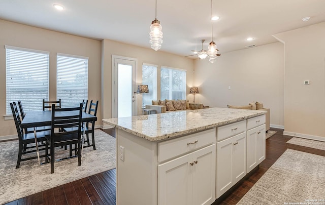 kitchen featuring a kitchen island, ceiling fan, dark hardwood / wood-style floors, white cabinetry, and hanging light fixtures