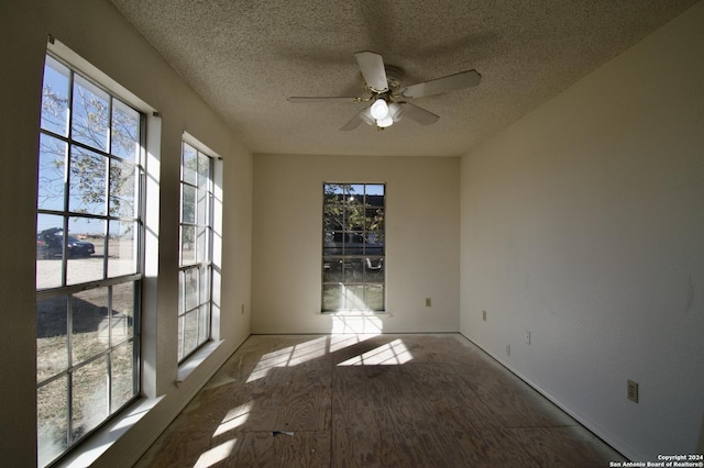 empty room with ceiling fan and a textured ceiling