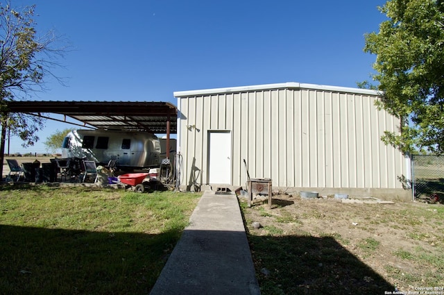 view of outdoor structure with a carport and a lawn