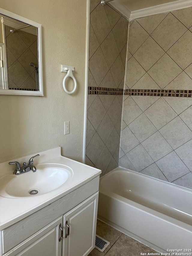 bathroom with tile patterned flooring, vanity, tiled shower / bath, and crown molding