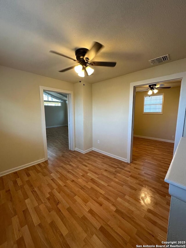 empty room featuring a textured ceiling, light hardwood / wood-style flooring, and ceiling fan