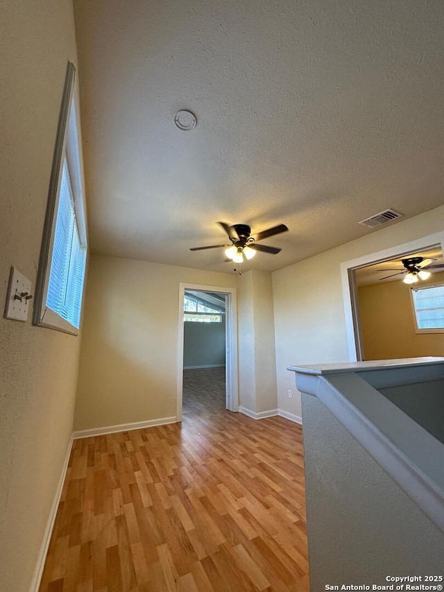 empty room featuring ceiling fan, light hardwood / wood-style floors, and a textured ceiling