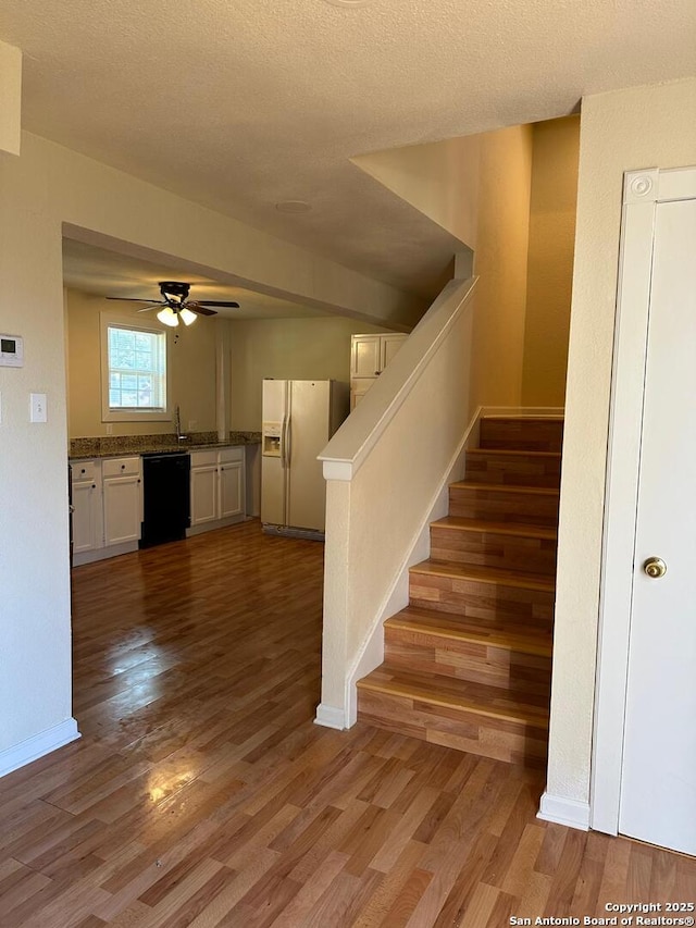 stairs featuring ceiling fan, a textured ceiling, and hardwood / wood-style flooring