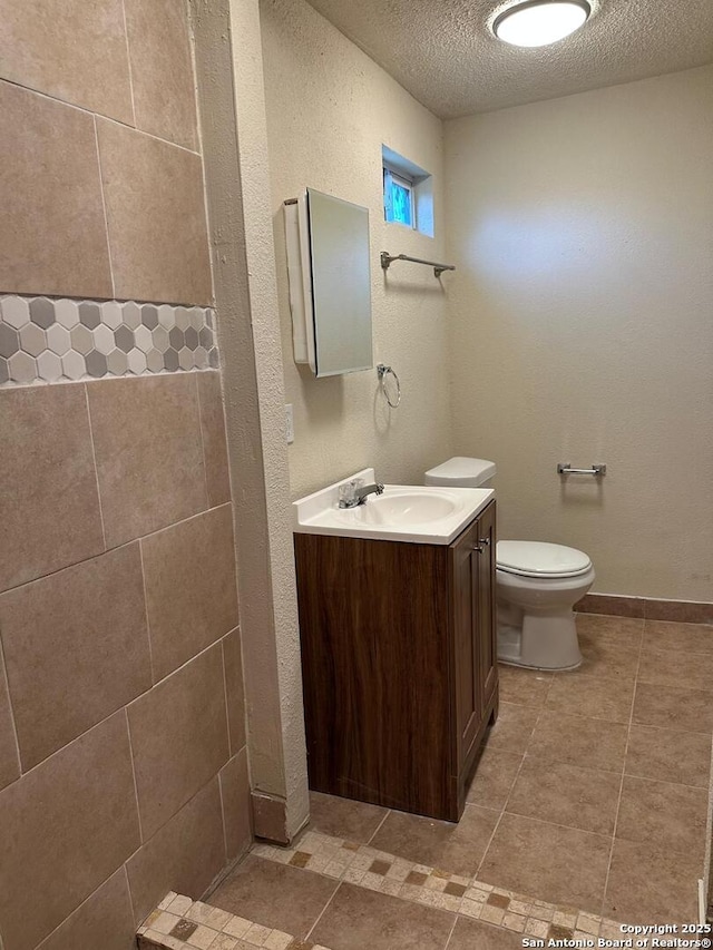 bathroom with vanity, toilet, and a textured ceiling