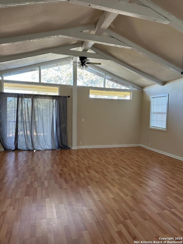 unfurnished room with hardwood / wood-style flooring, lofted ceiling with beams, and ceiling fan