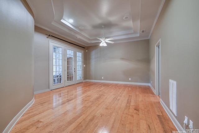 empty room with a tray ceiling, crown molding, light hardwood / wood-style flooring, and ceiling fan