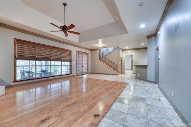 interior space with a tray ceiling, ceiling fan, ornamental molding, and light hardwood / wood-style floors