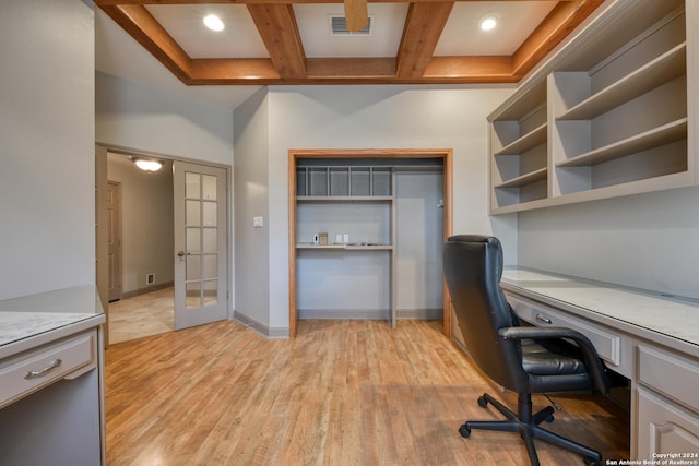 unfurnished office featuring coffered ceiling, french doors, light wood-type flooring, built in desk, and beam ceiling