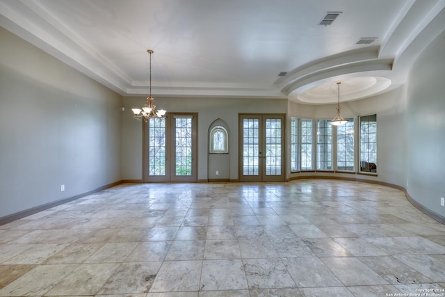 unfurnished room featuring an inviting chandelier, a raised ceiling, and french doors