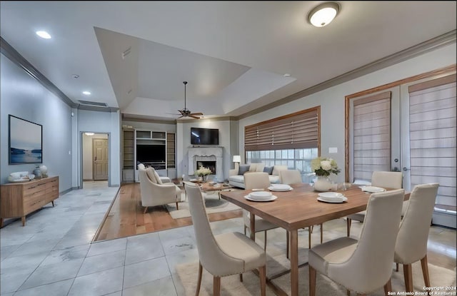 dining space with ceiling fan, french doors, crown molding, a tray ceiling, and light tile patterned floors