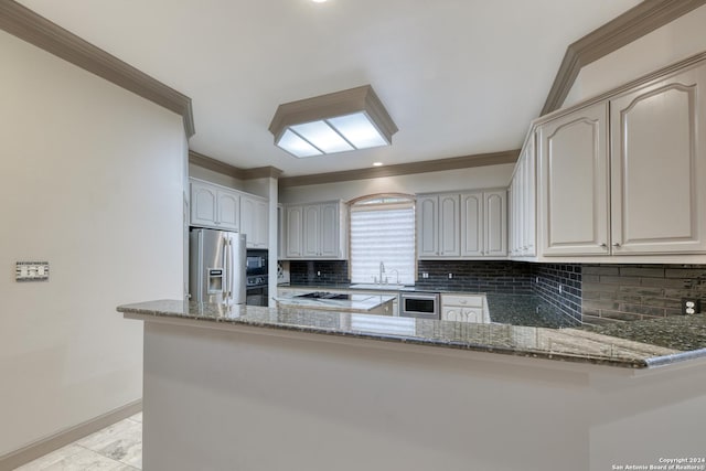 kitchen with black appliances, kitchen peninsula, backsplash, and dark stone counters