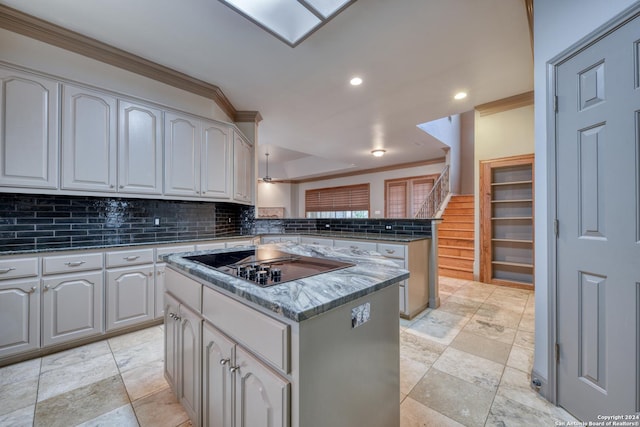 kitchen with black electric stovetop, decorative backsplash, ornamental molding, a kitchen island, and kitchen peninsula