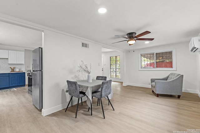 dining room featuring ceiling fan, a wall mounted AC, and light hardwood / wood-style flooring