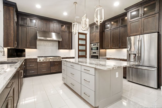 kitchen featuring tasteful backsplash, stainless steel appliances, sink, pendant lighting, and a kitchen island