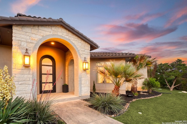 exterior entry at dusk with a lawn