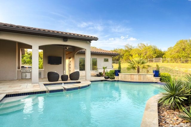 view of pool with an outdoor kitchen, a patio, ceiling fan, and a grill