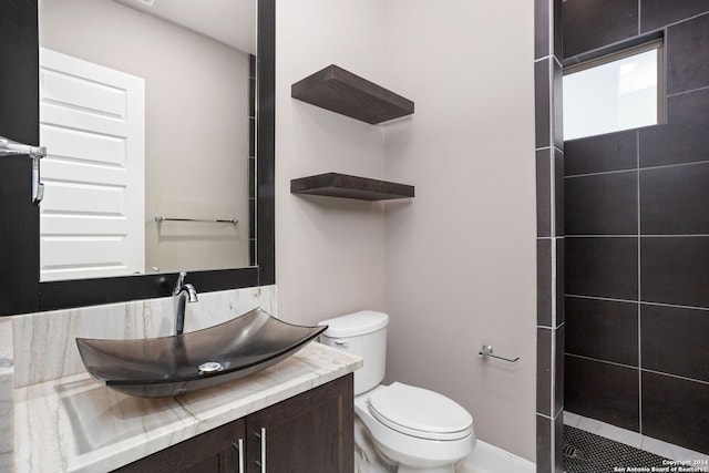 bathroom featuring vanity, toilet, and tiled shower