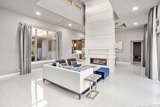 tiled living room with a fireplace and a towering ceiling