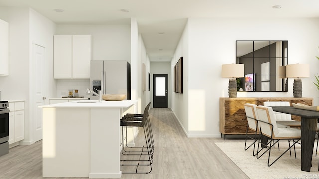 kitchen with white cabinetry, stainless steel appliances, backsplash, light hardwood / wood-style floors, and a kitchen bar