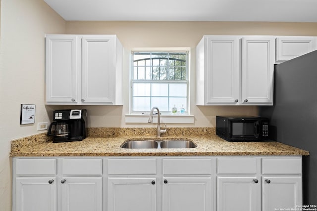 kitchen featuring light stone countertops, sink, and white cabinets