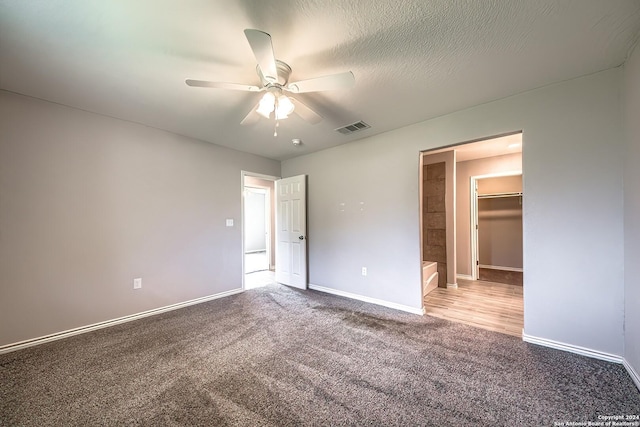 unfurnished bedroom featuring carpet flooring, a textured ceiling, ceiling fan, a spacious closet, and a closet