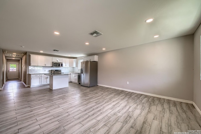 kitchen with a center island, stainless steel appliances, light hardwood / wood-style flooring, backsplash, and white cabinets