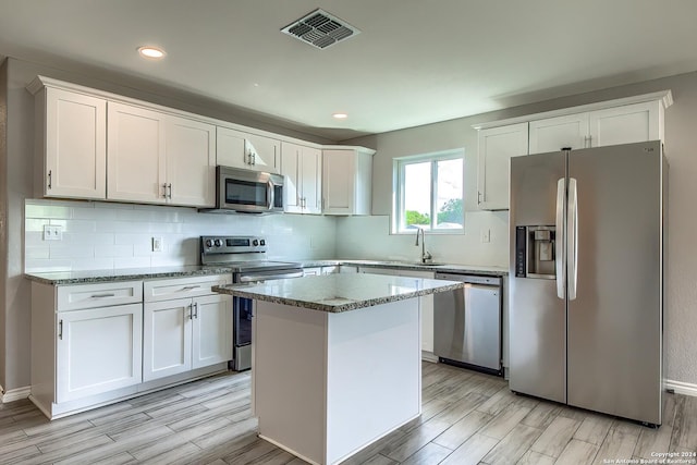 kitchen with a center island, white cabinets, light hardwood / wood-style flooring, and appliances with stainless steel finishes