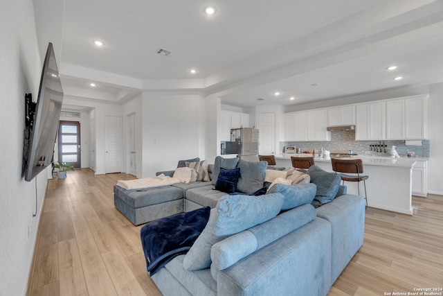 living room with a raised ceiling and light wood-type flooring