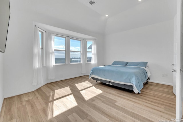 bedroom with light hardwood / wood-style floors and lofted ceiling