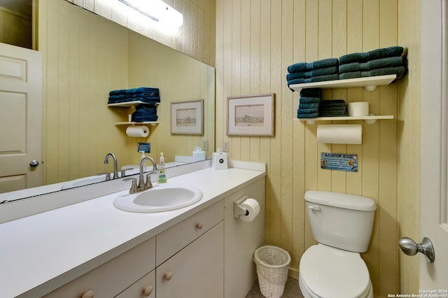 bathroom featuring wood walls, vanity, and toilet