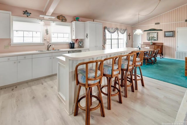 kitchen featuring pendant lighting, a center island, white cabinets, sink, and light hardwood / wood-style flooring