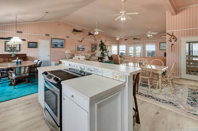 kitchen with stainless steel electric range oven, white cabinets, vaulted ceiling, a kitchen island, and light wood-type flooring