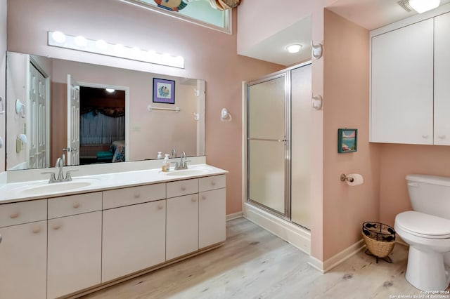 bathroom featuring vanity, hardwood / wood-style flooring, toilet, and a shower with door