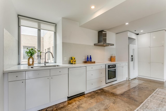 kitchen featuring backsplash, white appliances, sink, wall chimney range hood, and white cabinetry