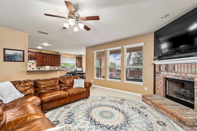 living room featuring light carpet, a textured ceiling, a brick fireplace, and ceiling fan