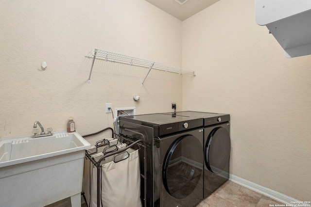 clothes washing area with washing machine and dryer and sink