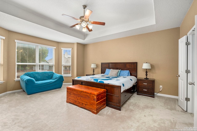 bedroom featuring ceiling fan, light carpet, and a tray ceiling