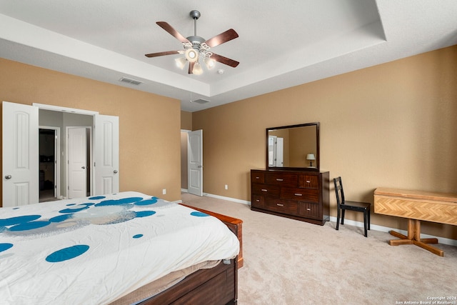 bedroom featuring ceiling fan, light carpet, and a tray ceiling